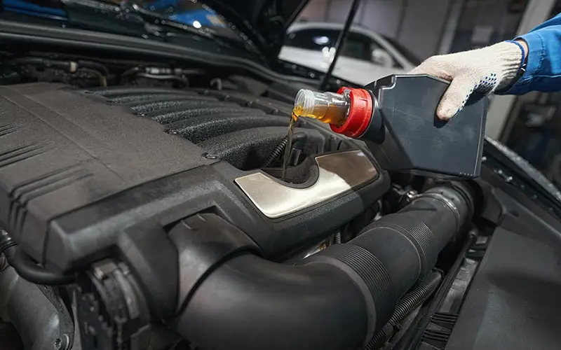 Technician pouring fresh motor oil into a car engine during an oil change in Flint, MI
