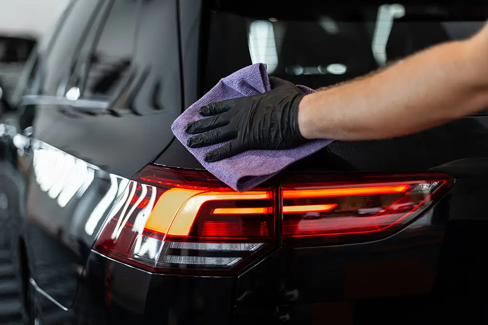 Auto detailer wiping down a vehicle, representing entry-level car wash careers and training